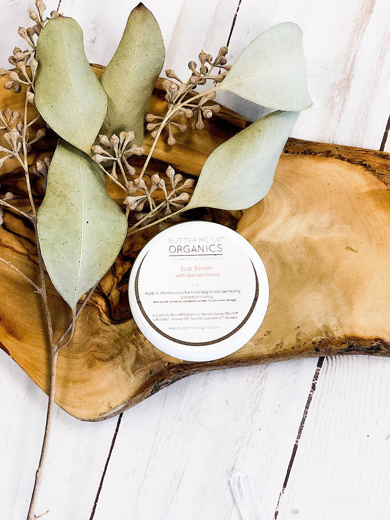 Scar Serum in eco-friendly packaging on a wooden tray with dried leaves.