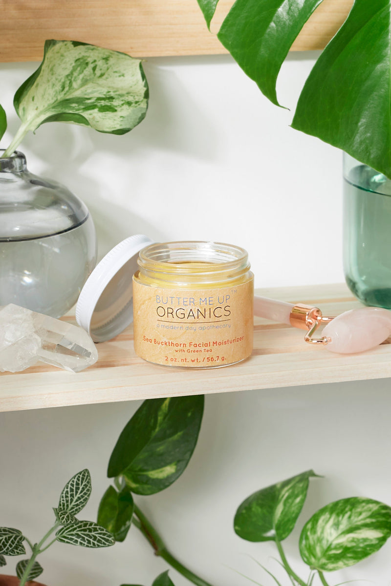 Organic Sea Buckthorn Facial Moisturizer jar on a shelf with plants and crystals.