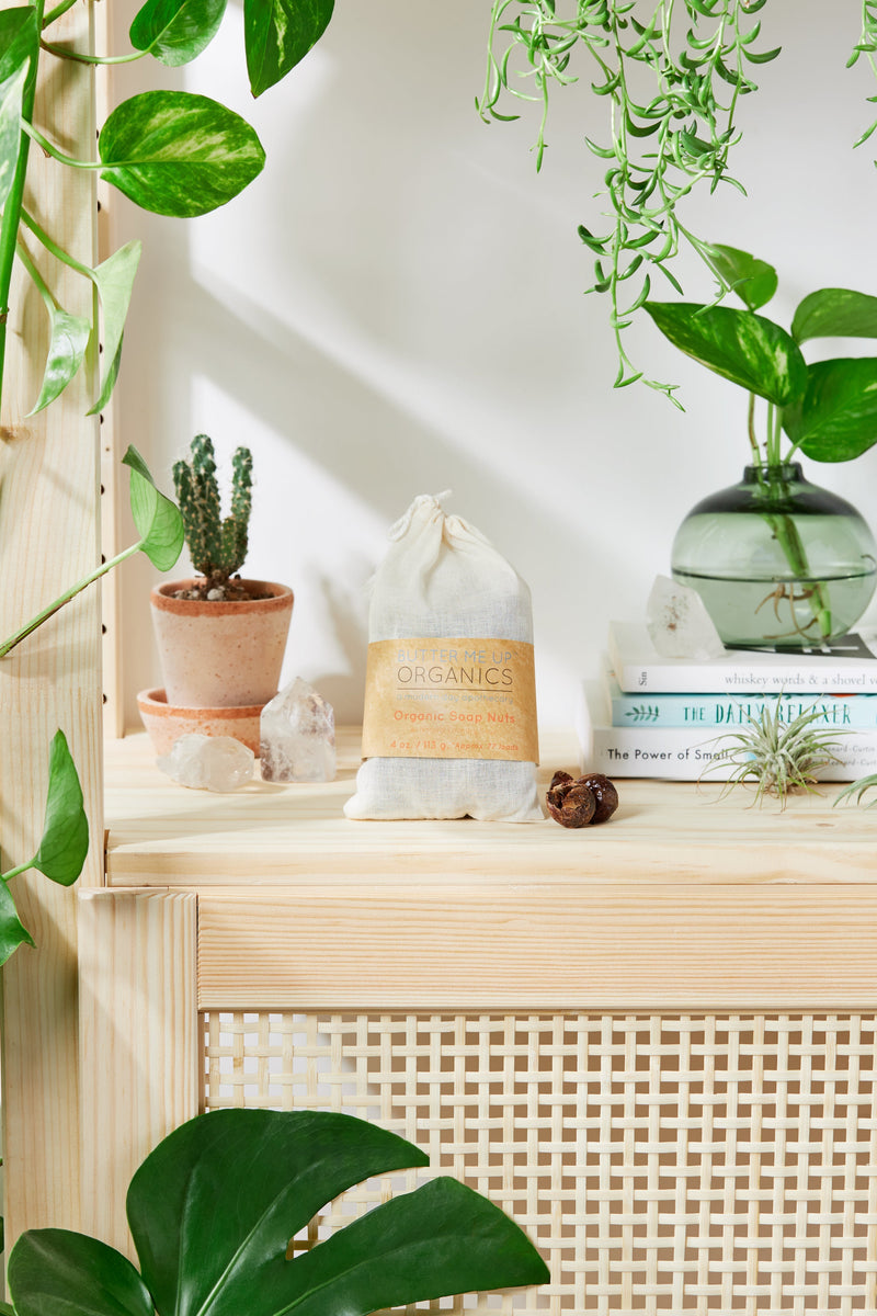 Organic soap nuts in a muslin bag on a wooden shelf with plants.