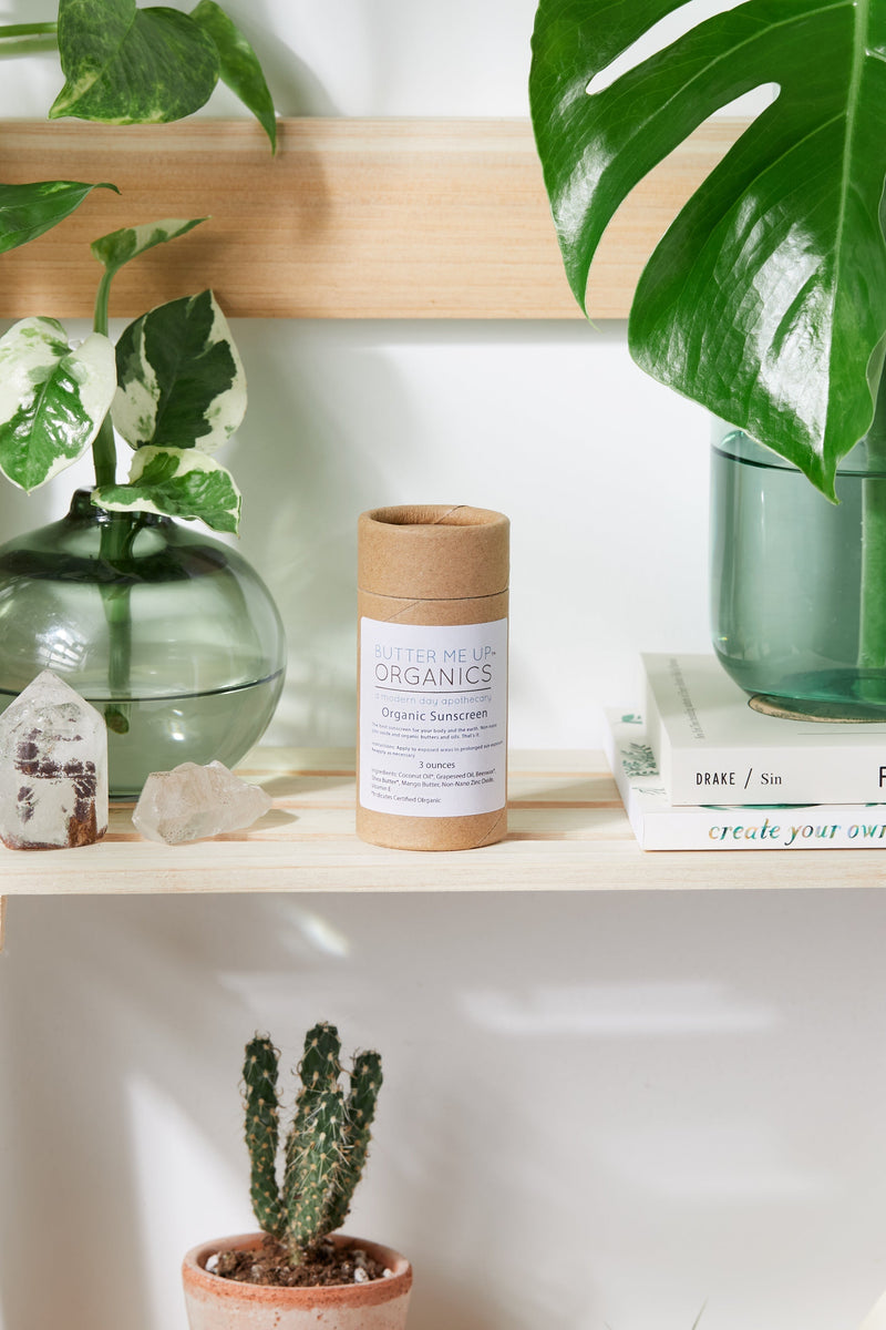 Natural organic sunscreen tube with non-nano zinc oxide on a shelf with plants and books.