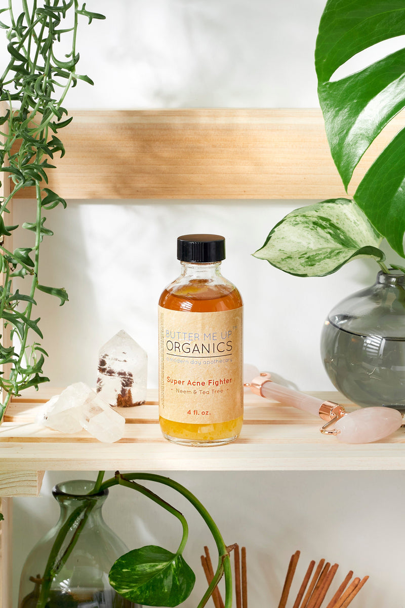 Super Acne Fighter organic acne treatment bottle on a shelf with plants and crystals.