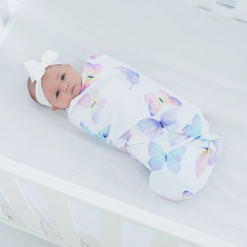 Buttery soft and stretchy butterfly swaddle blanket wrapping a baby in a crib.