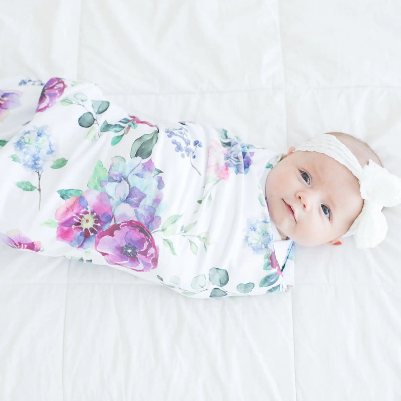 Buttery soft and stretchy swaddle blanket with blue floral pattern, wrapped around baby.