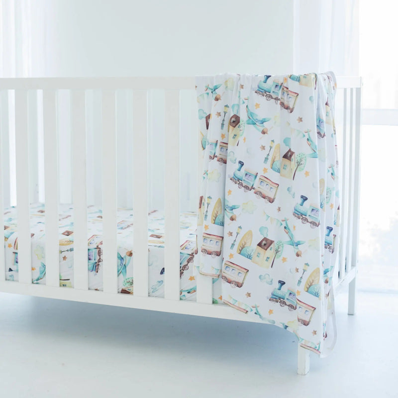 Buttery soft and stretchy swaddle blanket with airplane and train design in a nursery setting.