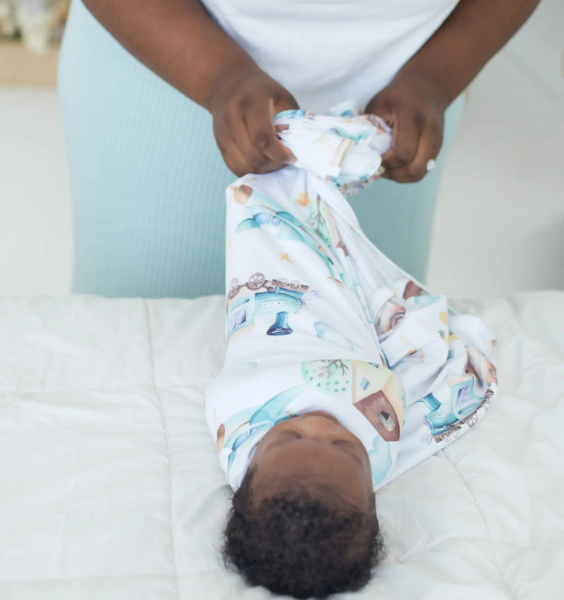 buttery soft and stretchy swaddle blanket with airplane and train design wrapping a baby