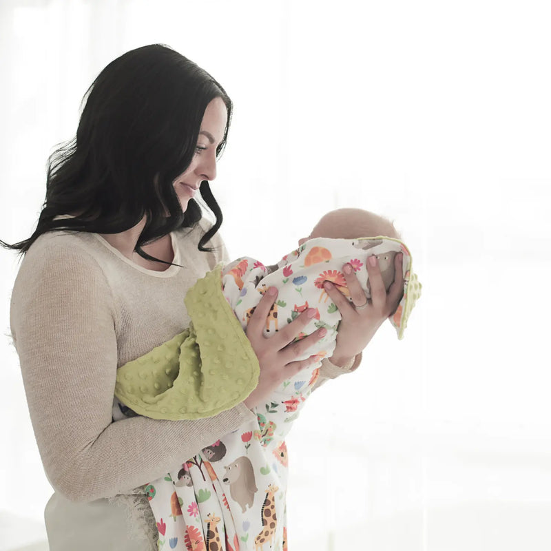 Baby and toddler minky blanket with zoo animal print, held by a woman, showcasing soft and sensory-friendly texture.
