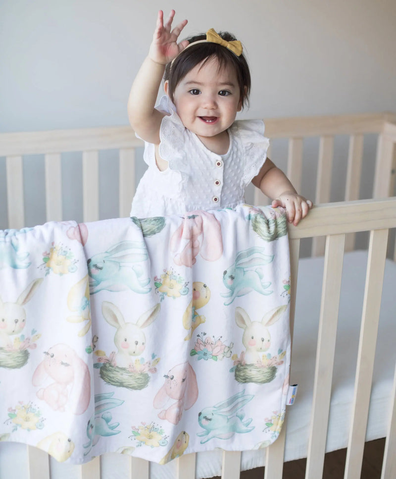 Baby & toddler minky blanket with bunny print in a crib setting with a child.