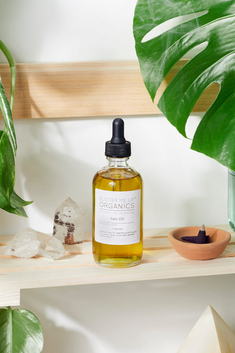 Organic Yoni Oil bottle with natural ingredients like olive oil and lavender on a wooden shelf.