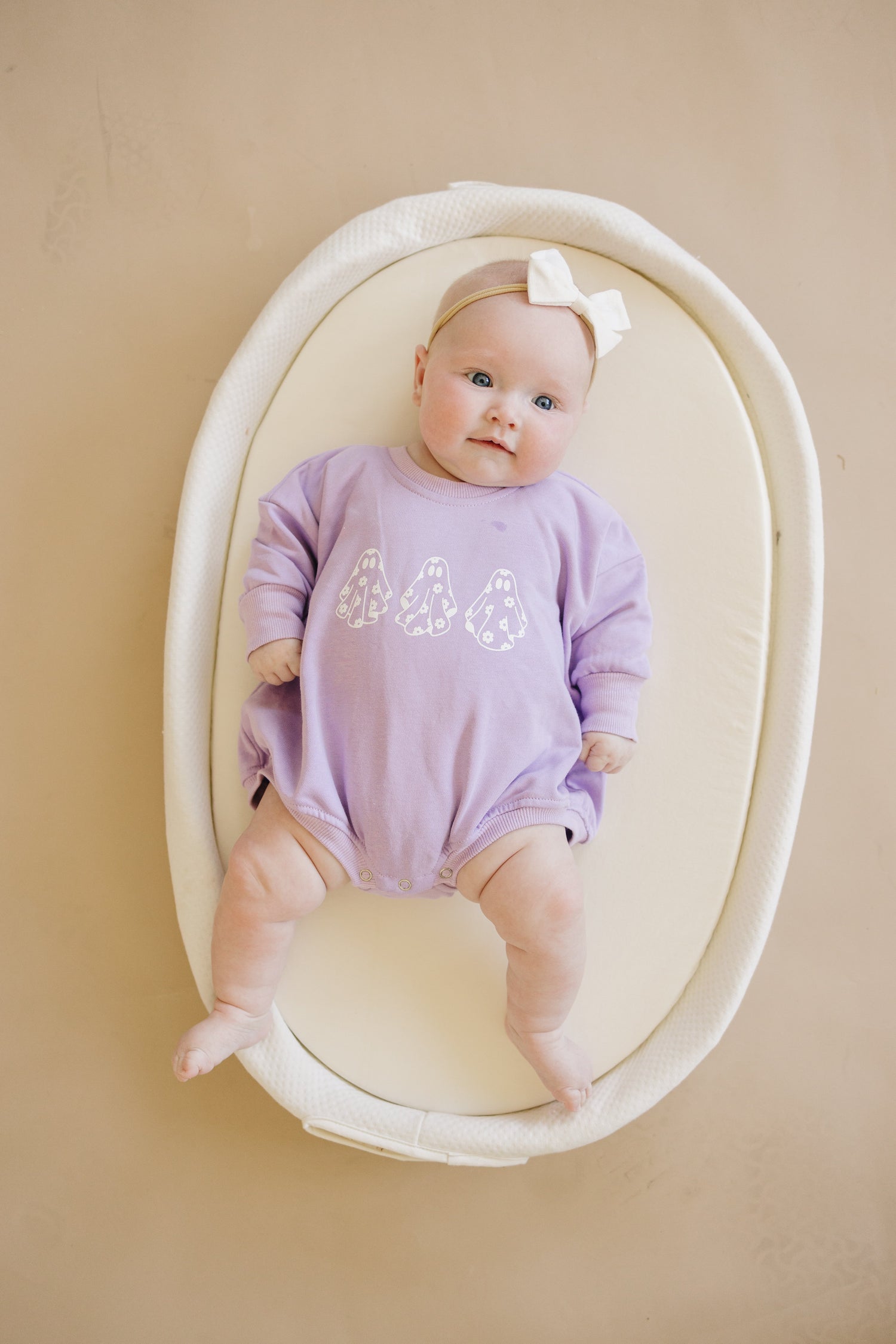 Oversized baby romper with a white ghost and daisy print and snap closure.
