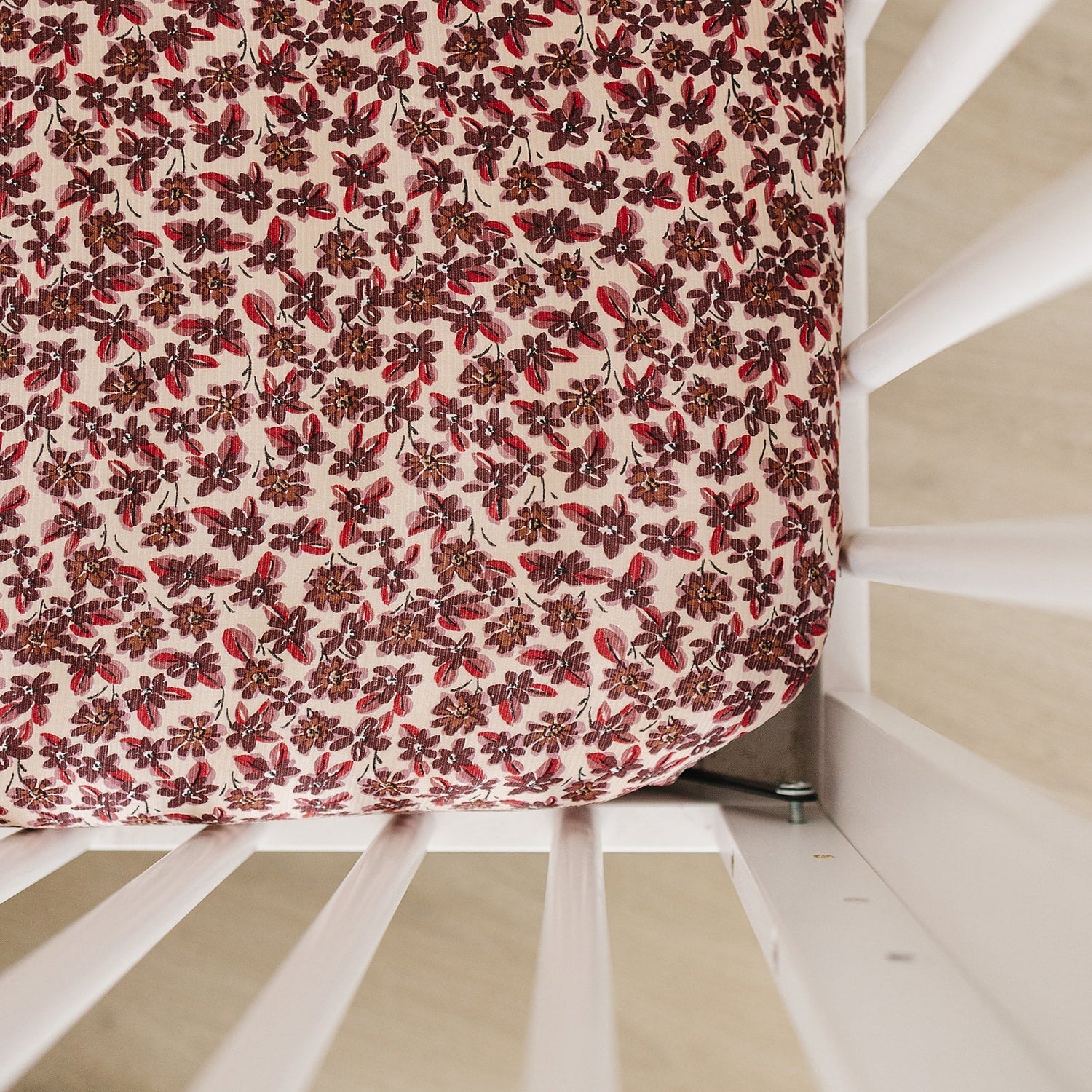 Ribbed bamboo crib sheet in an antique floral print fitted over a standard crib mattress