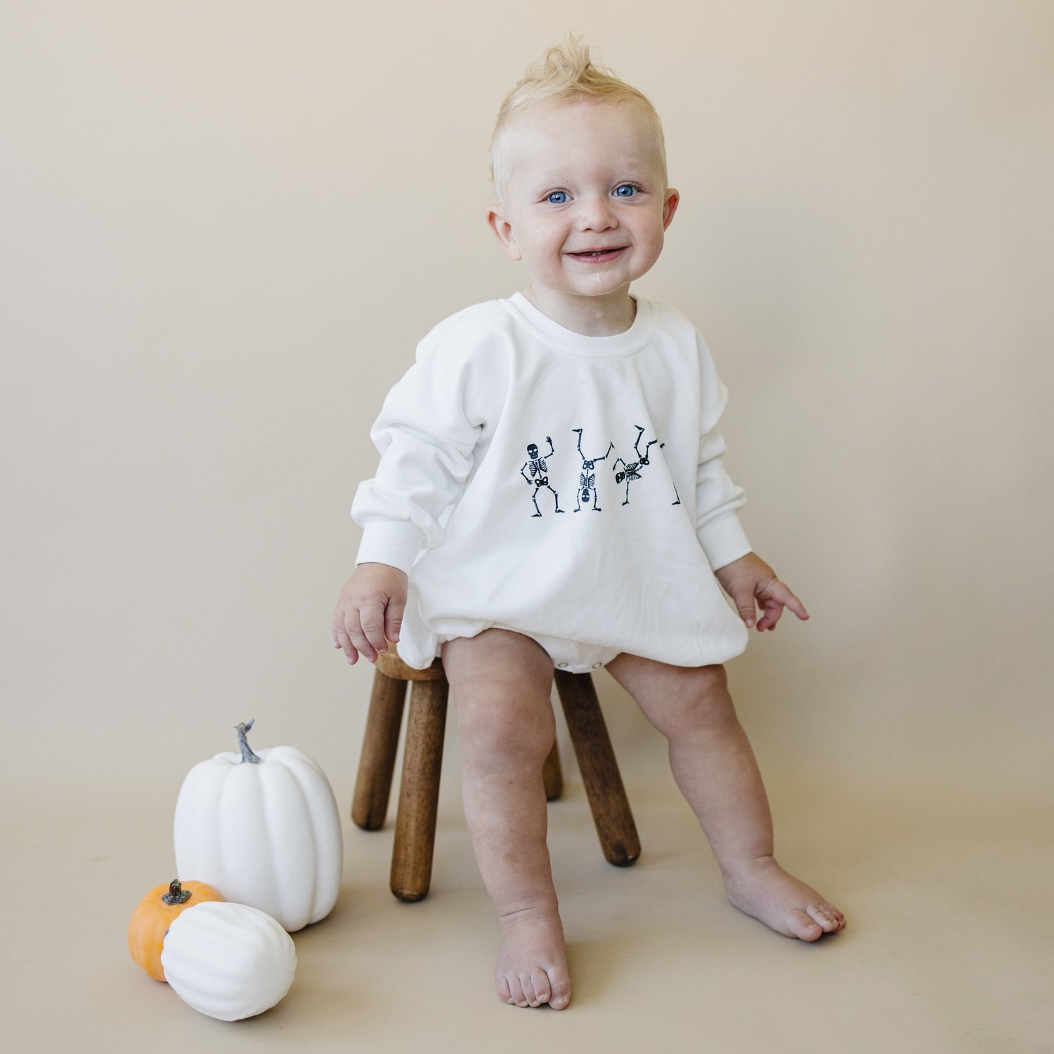 White oversized sweatshirt romper with screenprinted dancing skeletons Halloween design and snap crotch closure