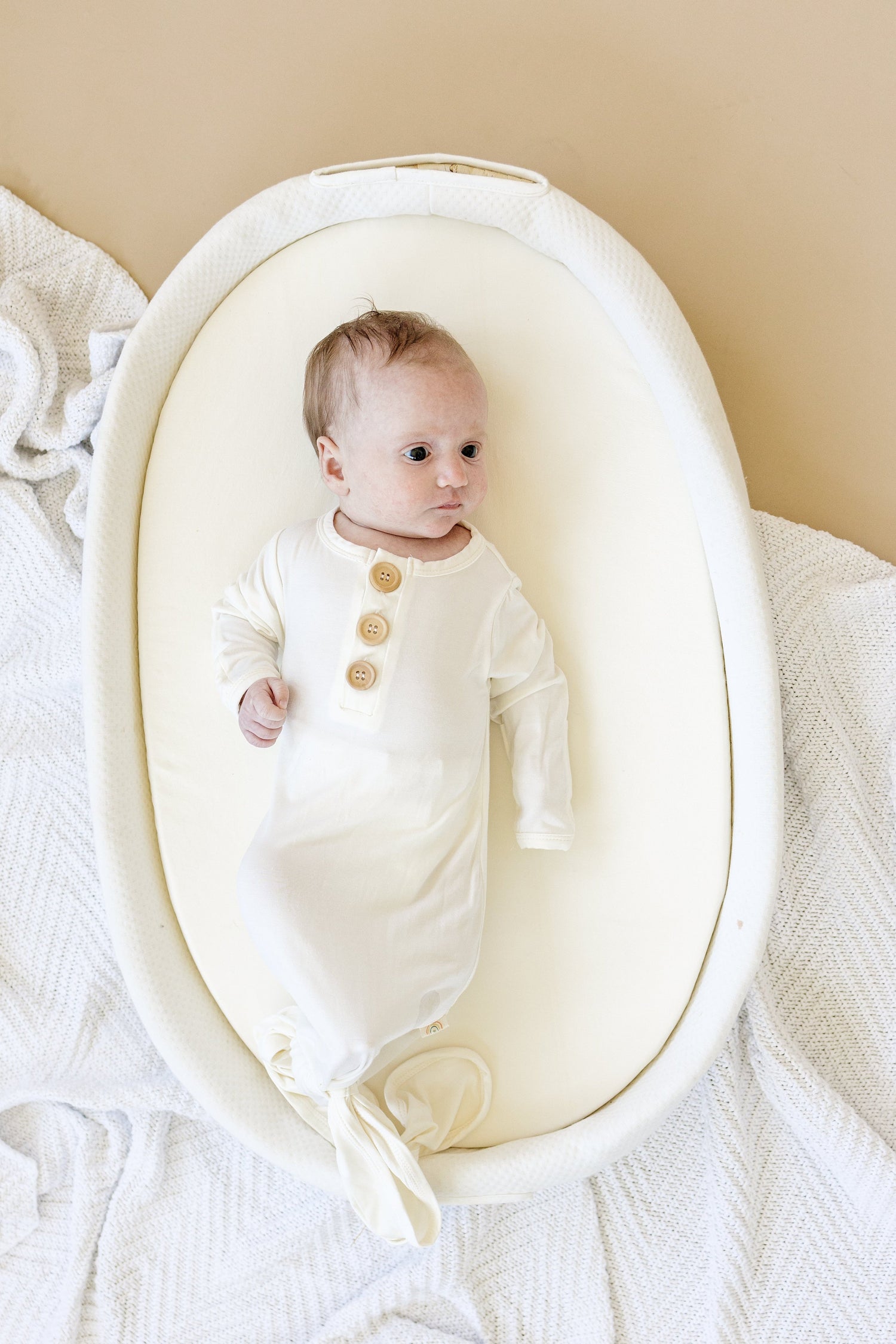 White newborn bamboo gown with a button accent and a gathered tie-bottom closure
