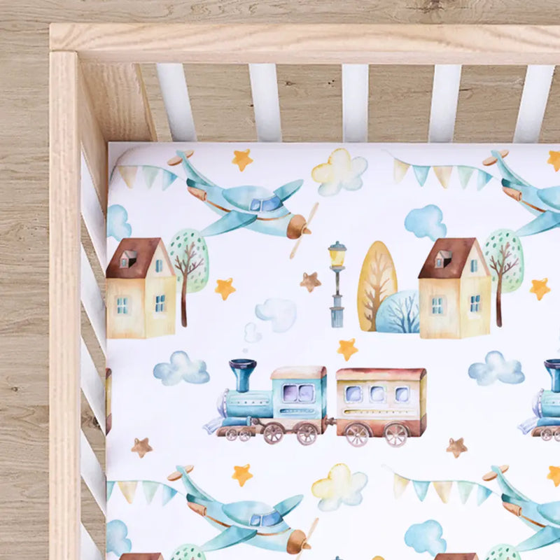 Fitted crib sheet with airplane and train pattern in crib.