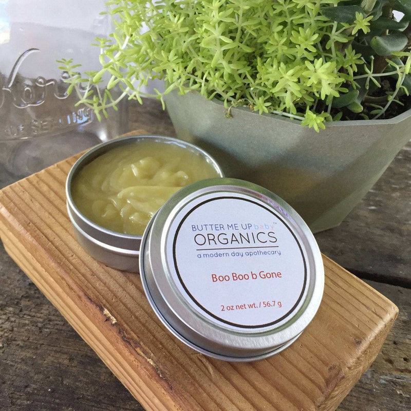 All Natural Neosporin salve in metal tin with herb-infused oils displayed on a wooden block.