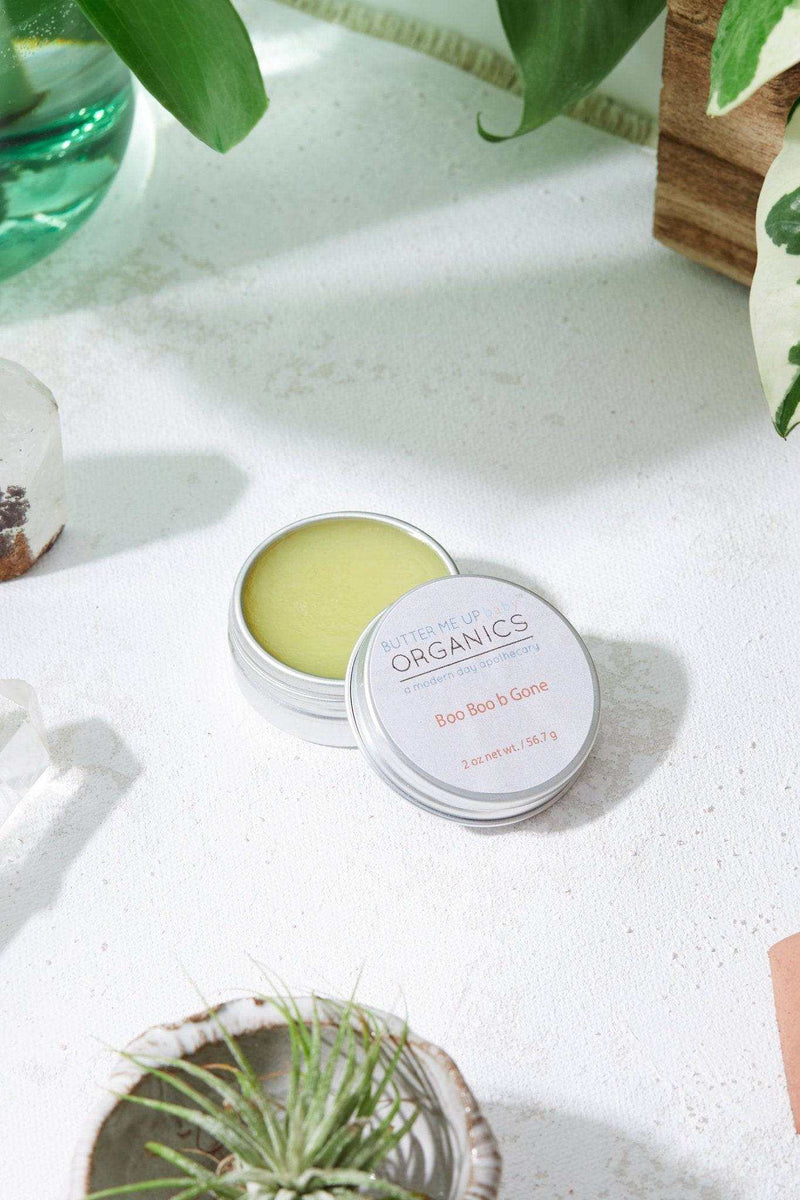 All Natural Neosporin salve in an open tin placed on a white surface with greenery.