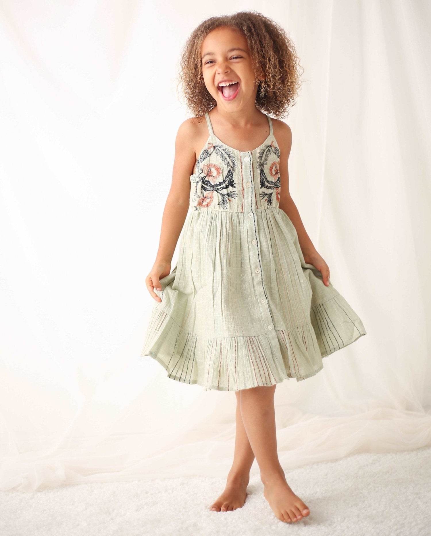 Girls' sage mini dress with red, black and metallic stripes, embroidered bodice, adjustable straps and front buttons