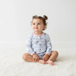 Long-sleeve bodysuit dress with blue bows, menorahs, Star of David and dreidel print on a light background