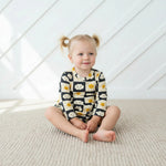 Checkered long-sleeve bodysuit dress with snap closure, worn by a smiling toddler