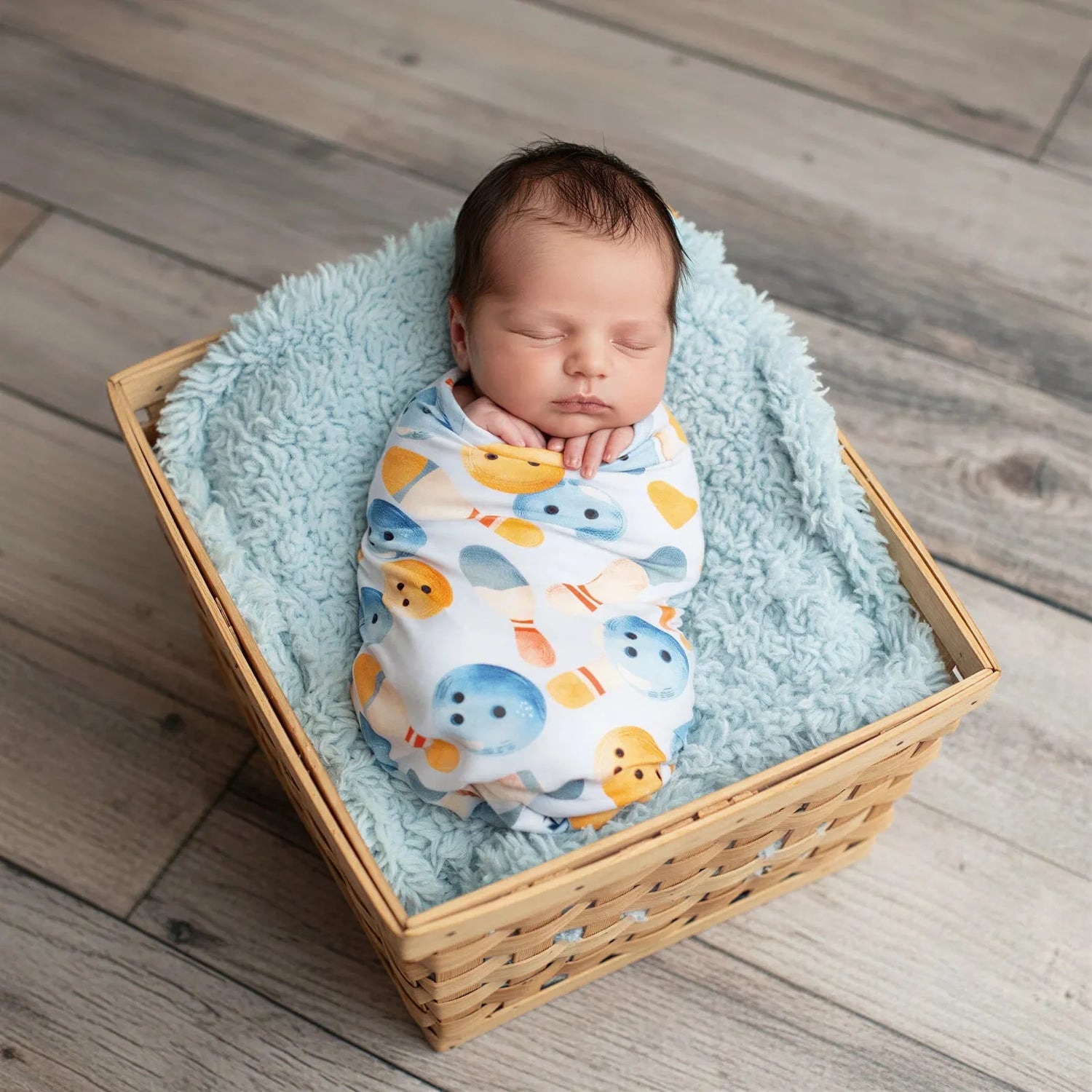 Bowling-print baby swaddle blanket with bowling pins and balls on a soft light background