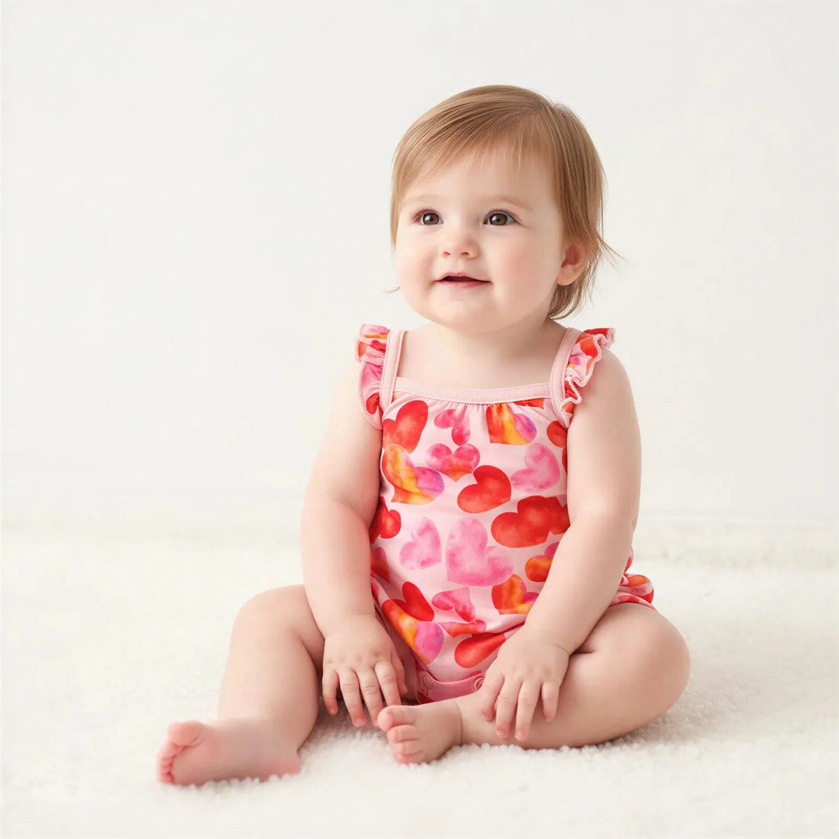Bubble romper with all-over heart print and flutter sleeves, snap closures along the legs