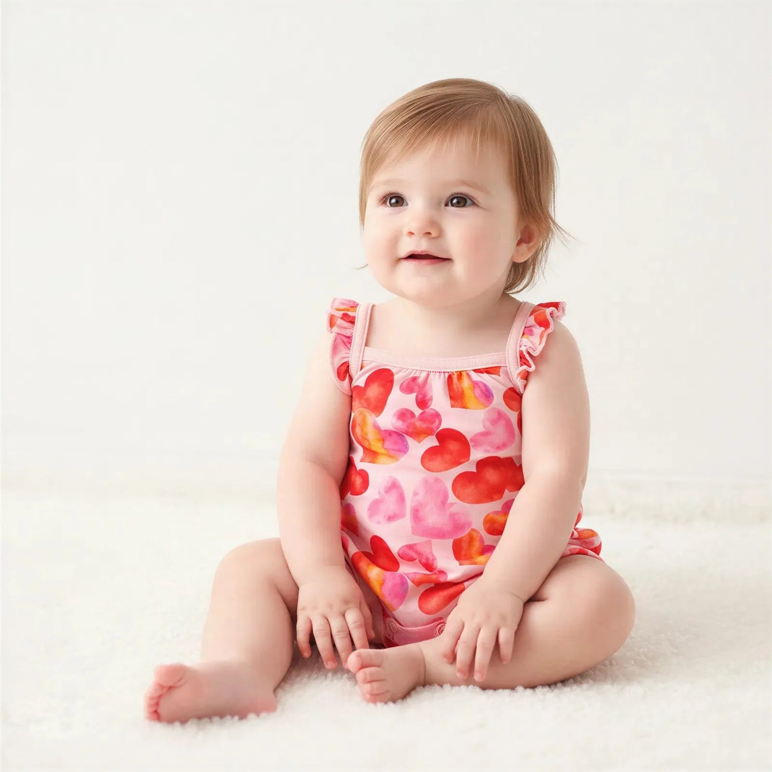 Bubble romper with all-over heart print and flutter sleeves, snap closures along the legs
