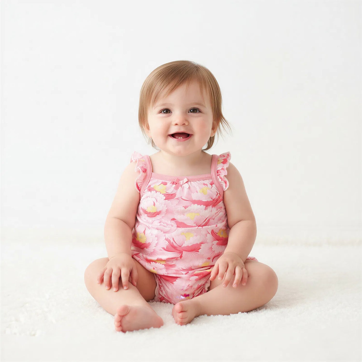 Blush floral bubble romper with flutter sleeves and snaps along the legs