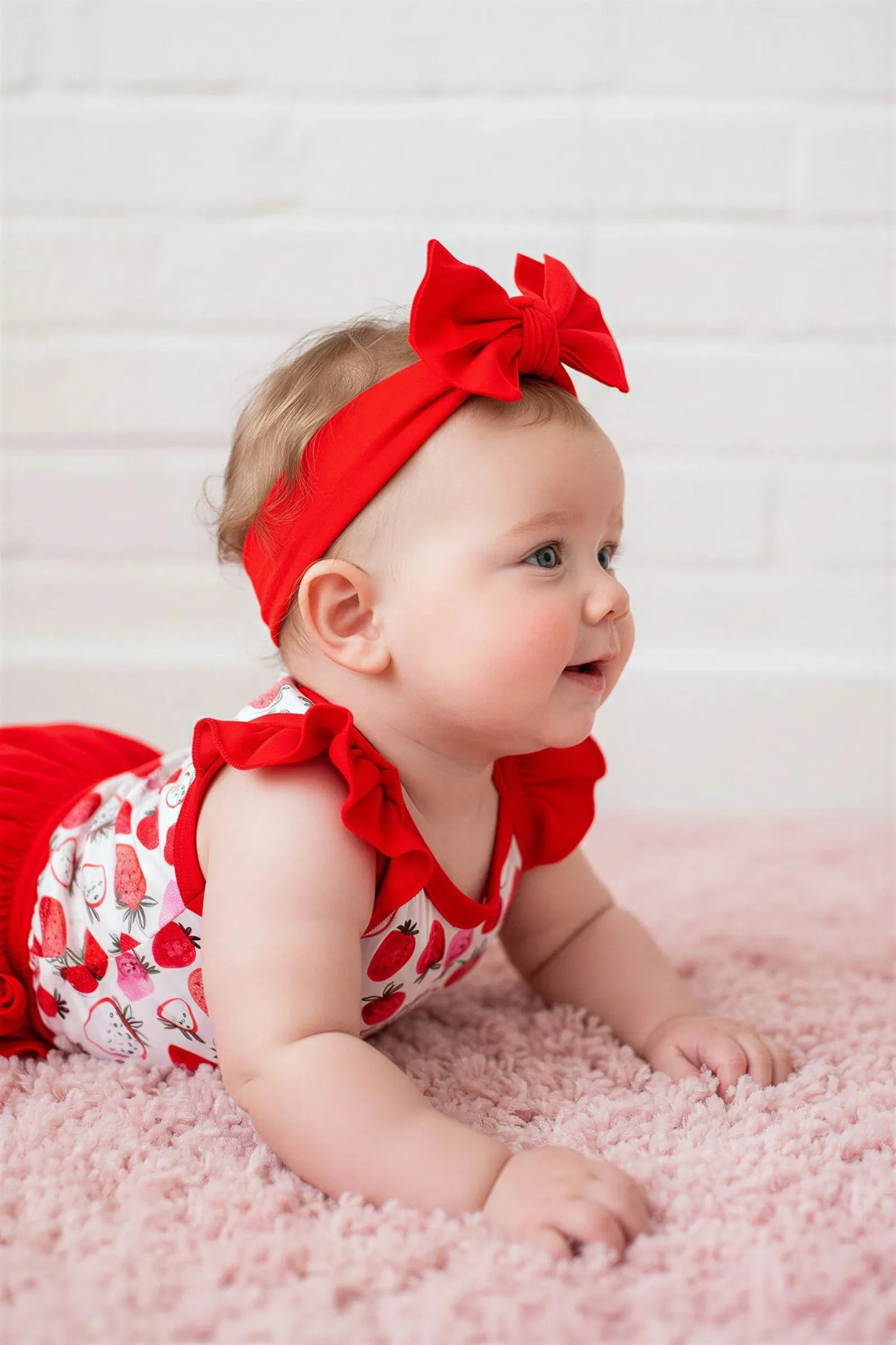 Baby set with strawberry-print bodysuit, ruffle-back bloomer, and matching headband in pink and red.