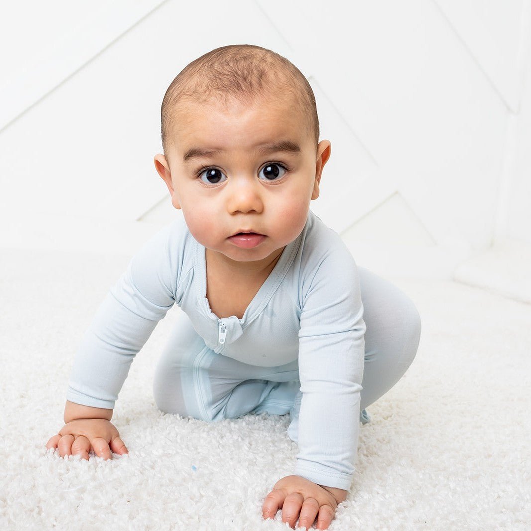Baby footie pajamas in solid light blue with footed legs and a full-length front zipper.