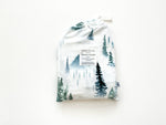 Soft organic bamboo changing pad cover in a green forest print, draped over a changing pad.