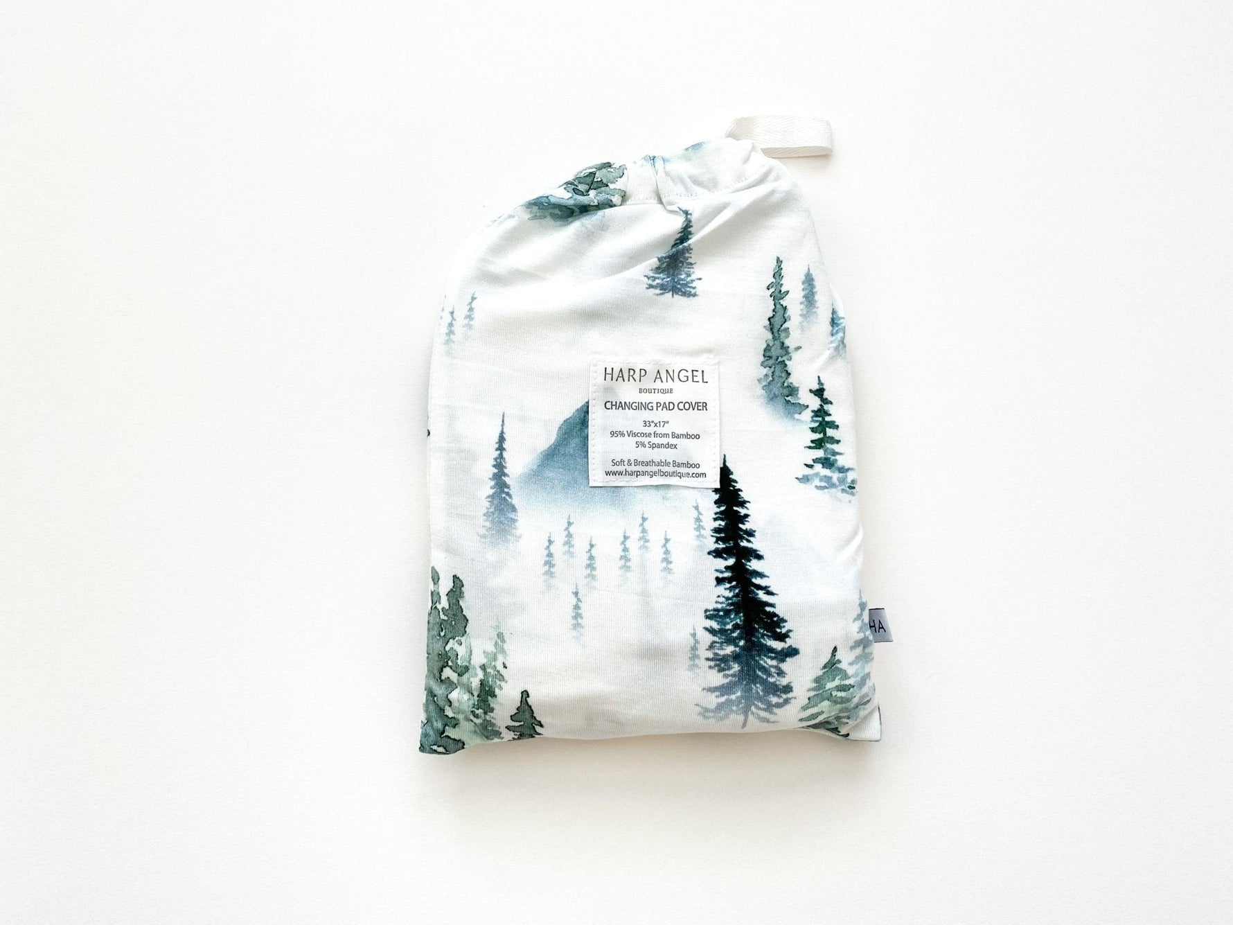 Soft organic bamboo changing pad cover in a green forest print, draped over a changing pad.