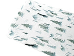 Soft organic bamboo changing pad cover in a green forest print, draped over a changing pad.