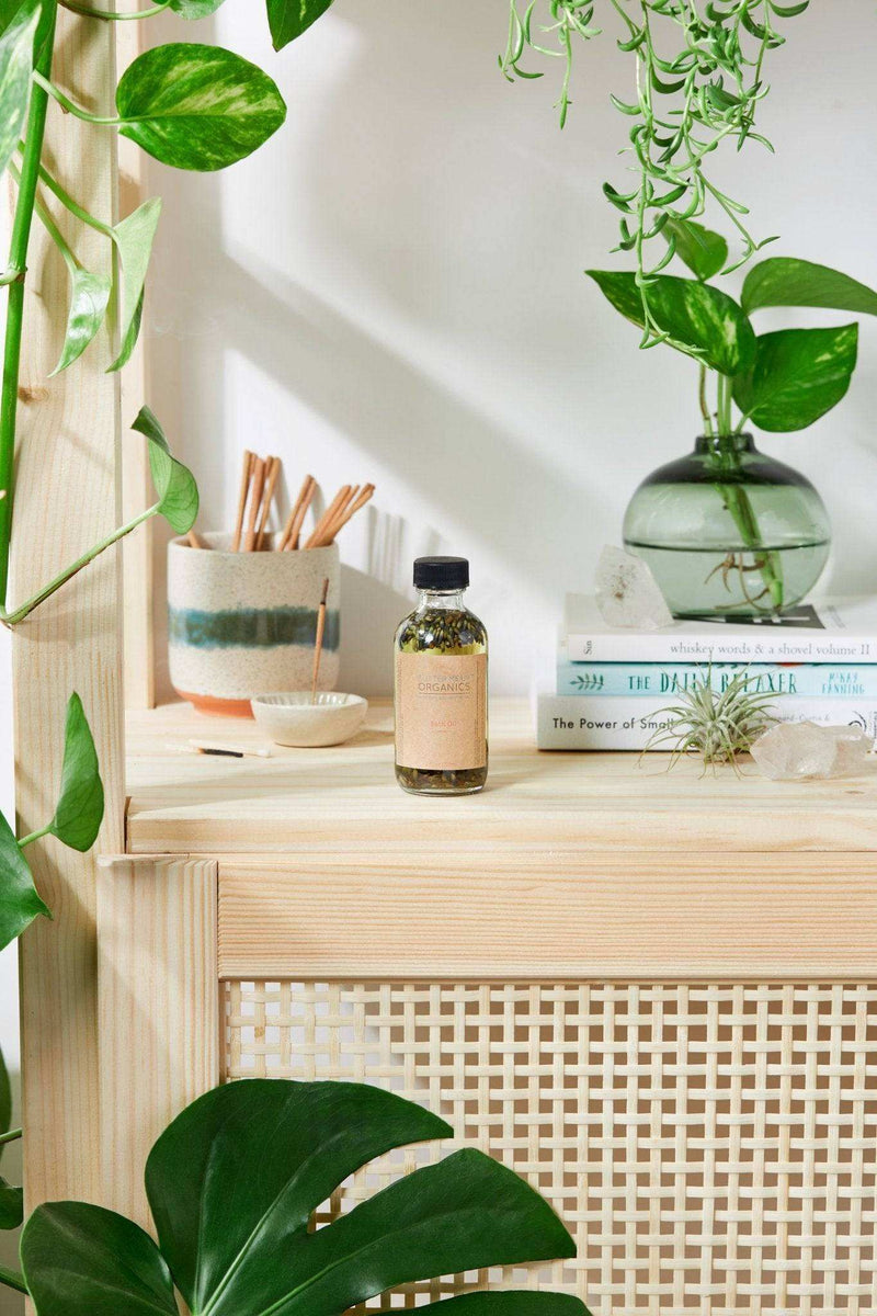 Bath oil with relaxing lavender on a shelf surrounded by plants.