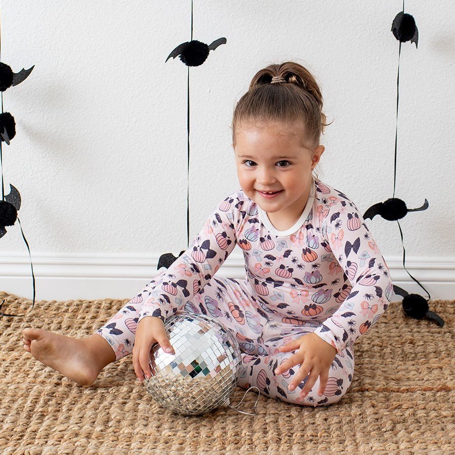 Long-sleeve two-piece pajama set with pink bows and polka dots on a toddler