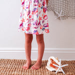 Short-sleeve toddler dress with a colorful seashell print in a beachy summer style.