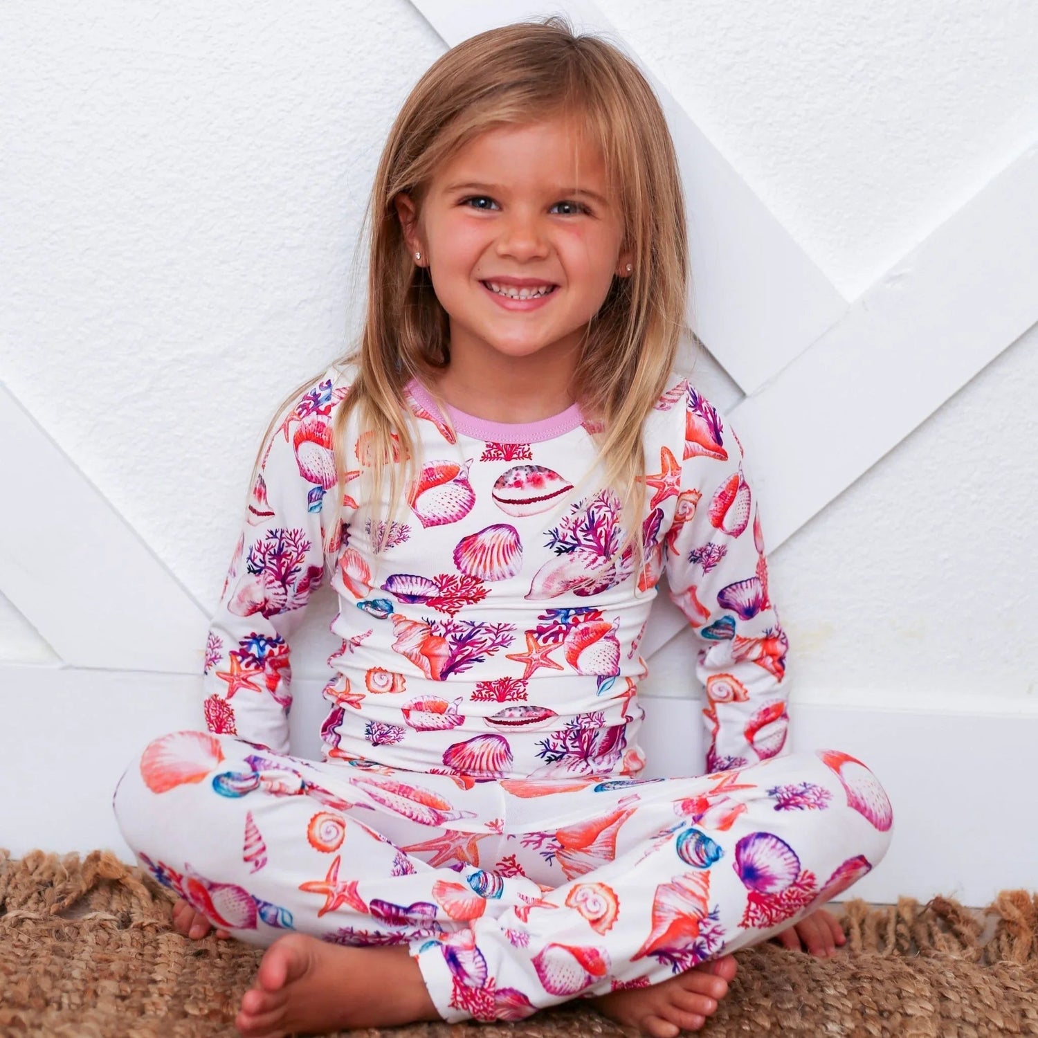 Toddler pajamas in a colorful seashell print on a light background, worn by a child.