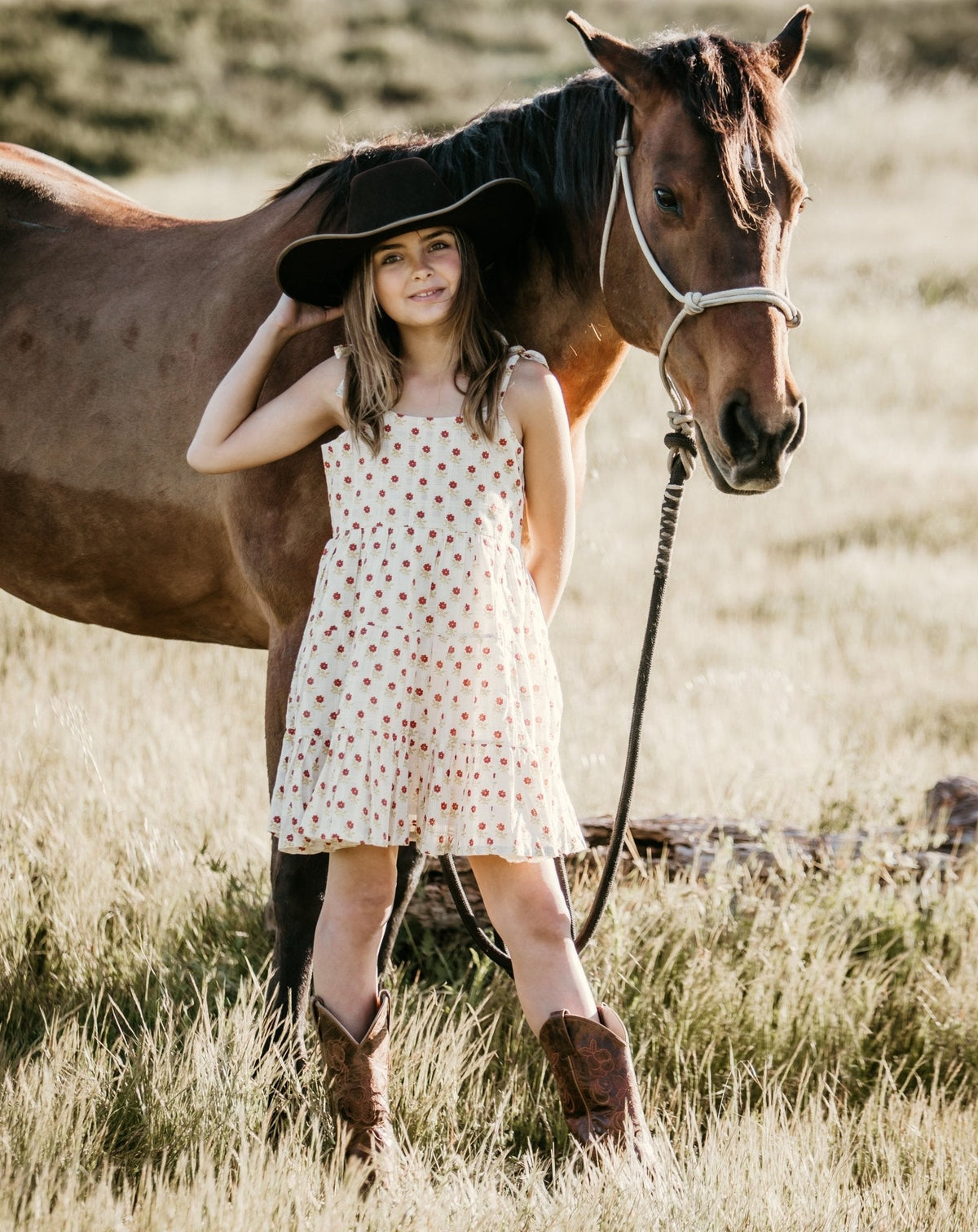 Baby dress in rust floral print with tie straps at the shoulders.
