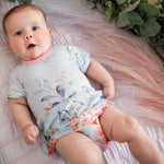 Pink blossom-print bodysuit dress with short sleeves and a ruffled skirt on a baby