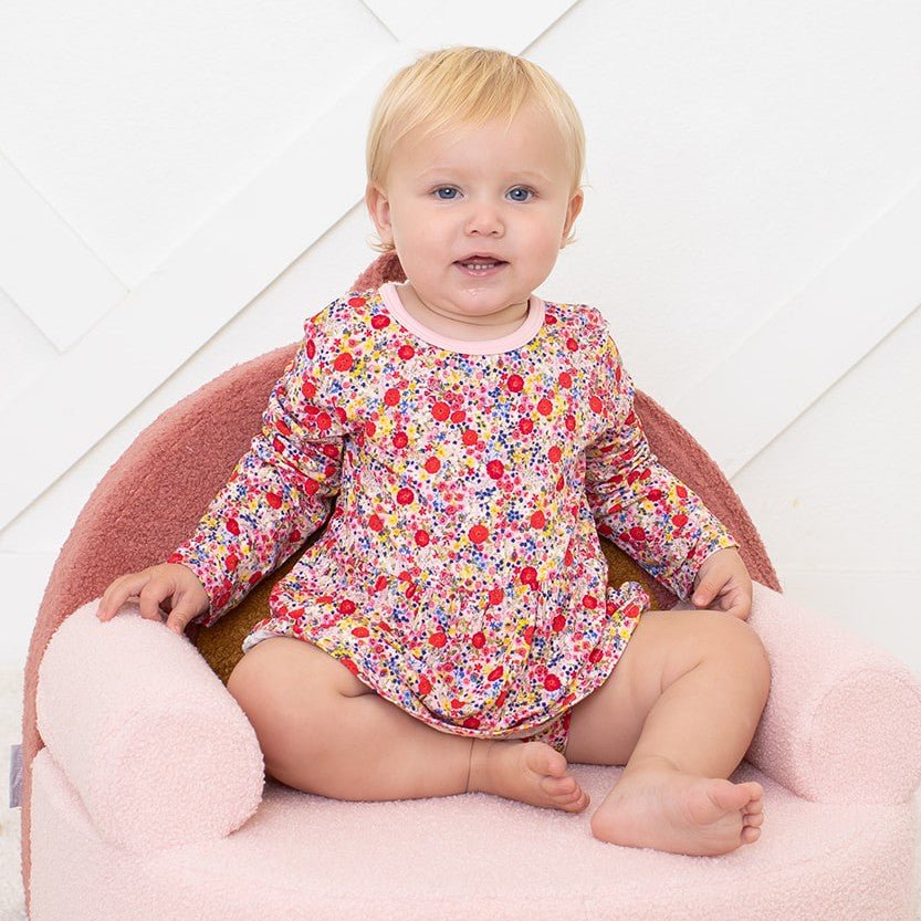 Blush pink long-sleeve bodysuit dress with a floral bloom print on a baby