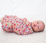 Blush pink floral swaddle blanket laid flat showing the blooming pattern.