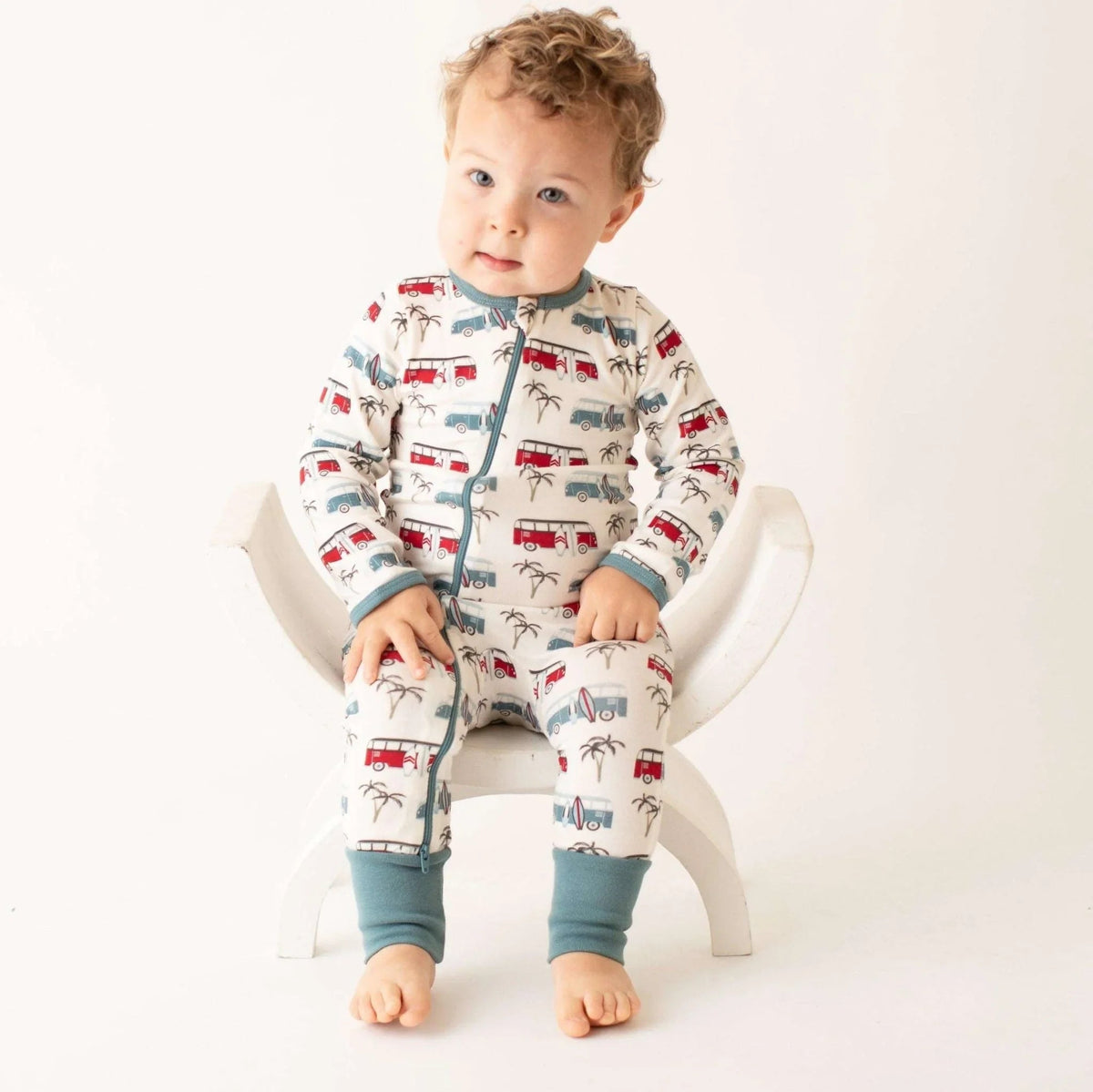 Baby coverall with a skateboard and bus print, dual zipper front and cuffed ankles.