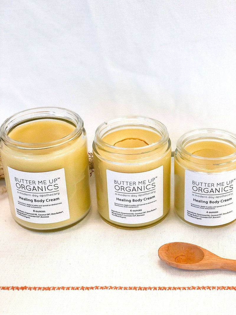 Organic body cream in glass jars with a wooden spoon.