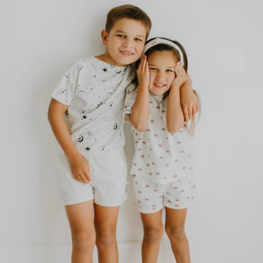Finn + Emma organic baby shorts in natural white with a playful red crab print.