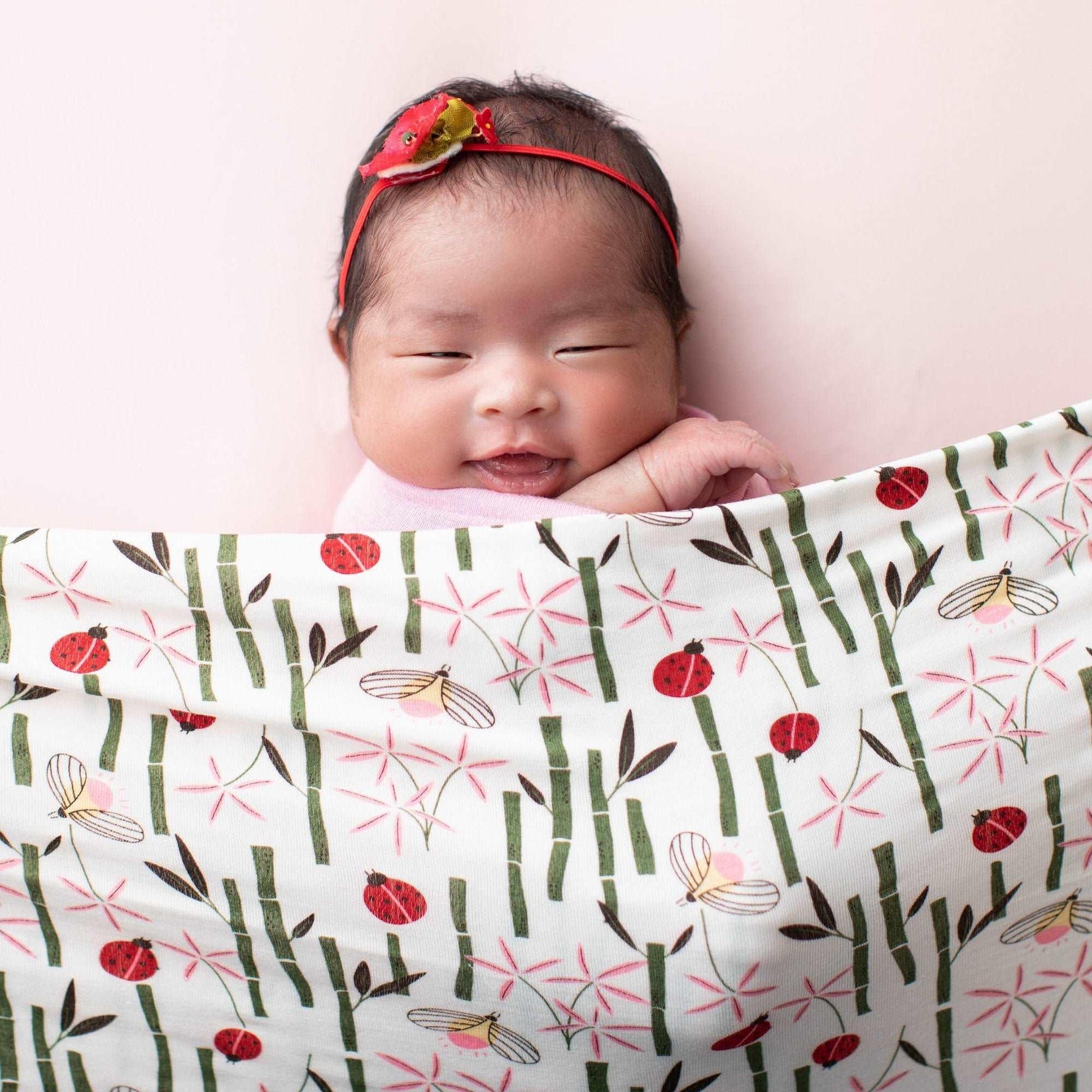 Square baby swaddle blanket with a pink insect and bug pattern