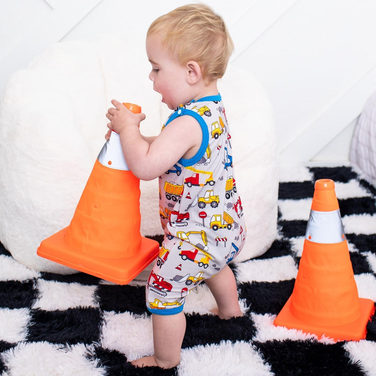 Sleeveless baby shortall in a builders print with snap closures at the shoulders and legs