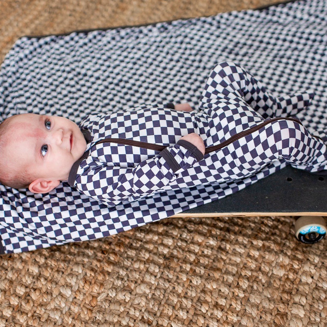 Baby footie pajamas in a charcoal and gray checkered pattern with a full-length zipper and footed legs.