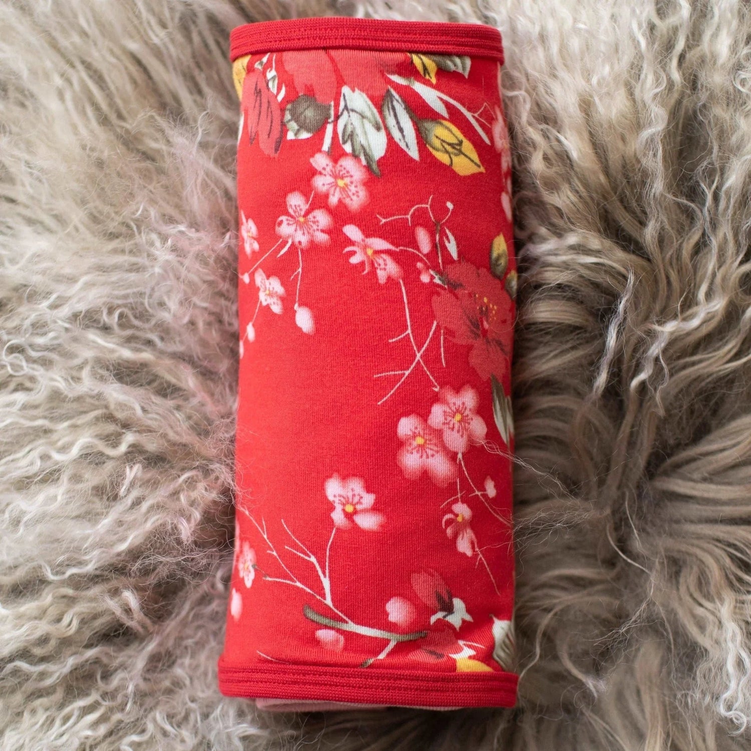 Baby swaddle blanket with red cherry blossom pattern spread out flat