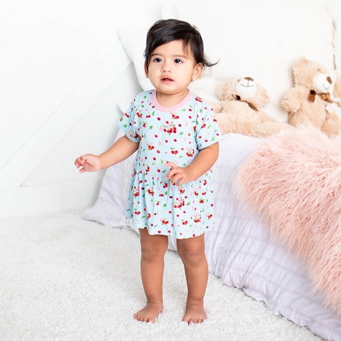 Short-sleeve baby bodysuit dress in a cherry print, with a flared skirt and snaps at the bottom