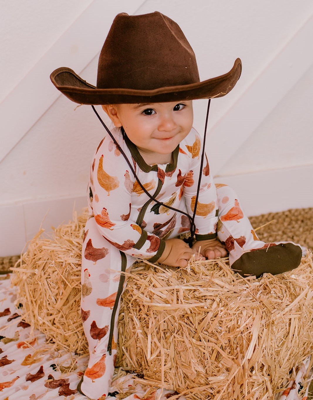 Baby footie pajamas in a chicken print with a two-way zipper down the front and footed legs.