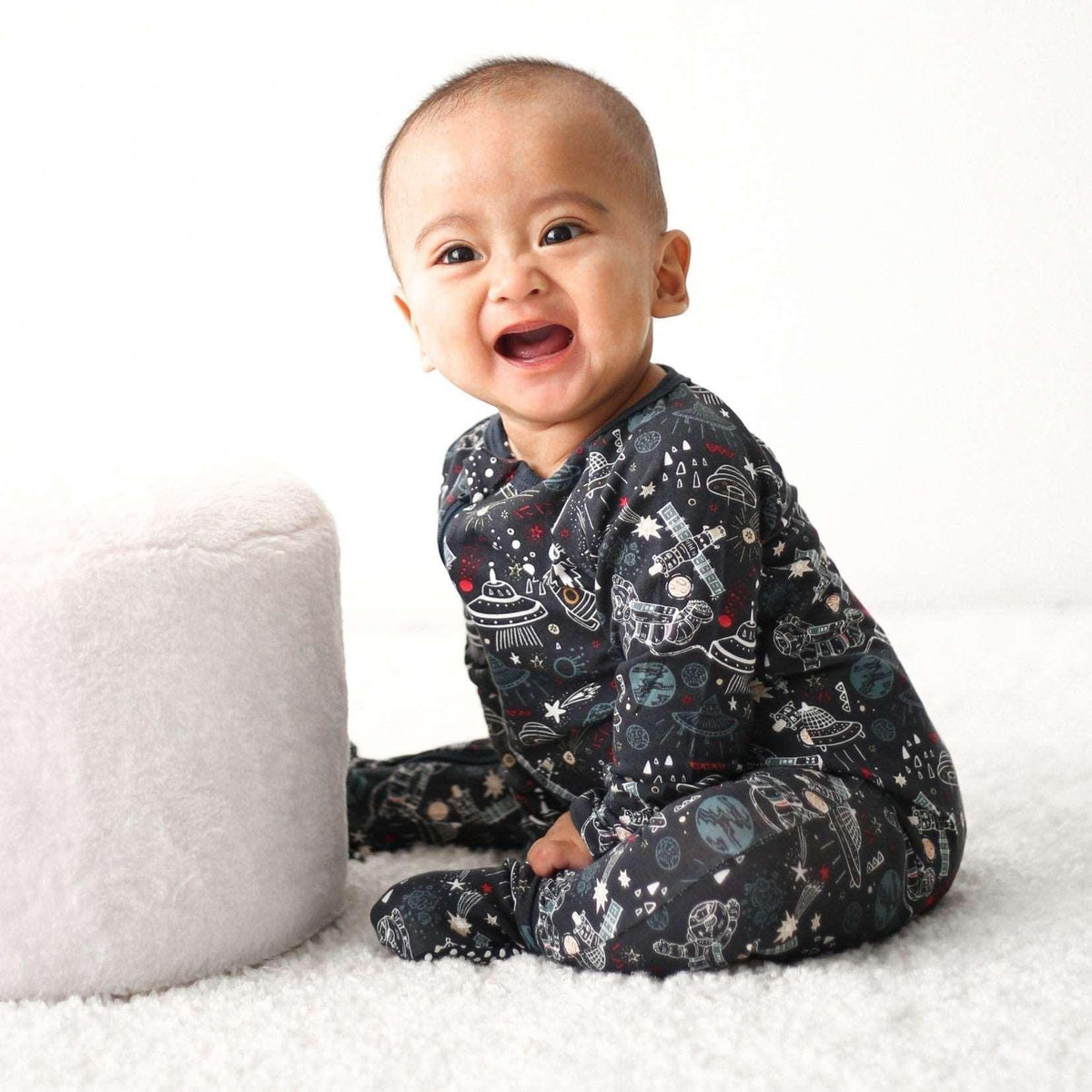 Baby footie pajamas in a dark midnight cosmic print with long sleeves and covered feet