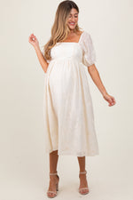 Cream maternity midi dress with delicate floral embroidery, puff sleeves, and a comfortable fit.